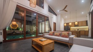 Un amplio salón con sofá, mesa de centro y vista a una piscina.