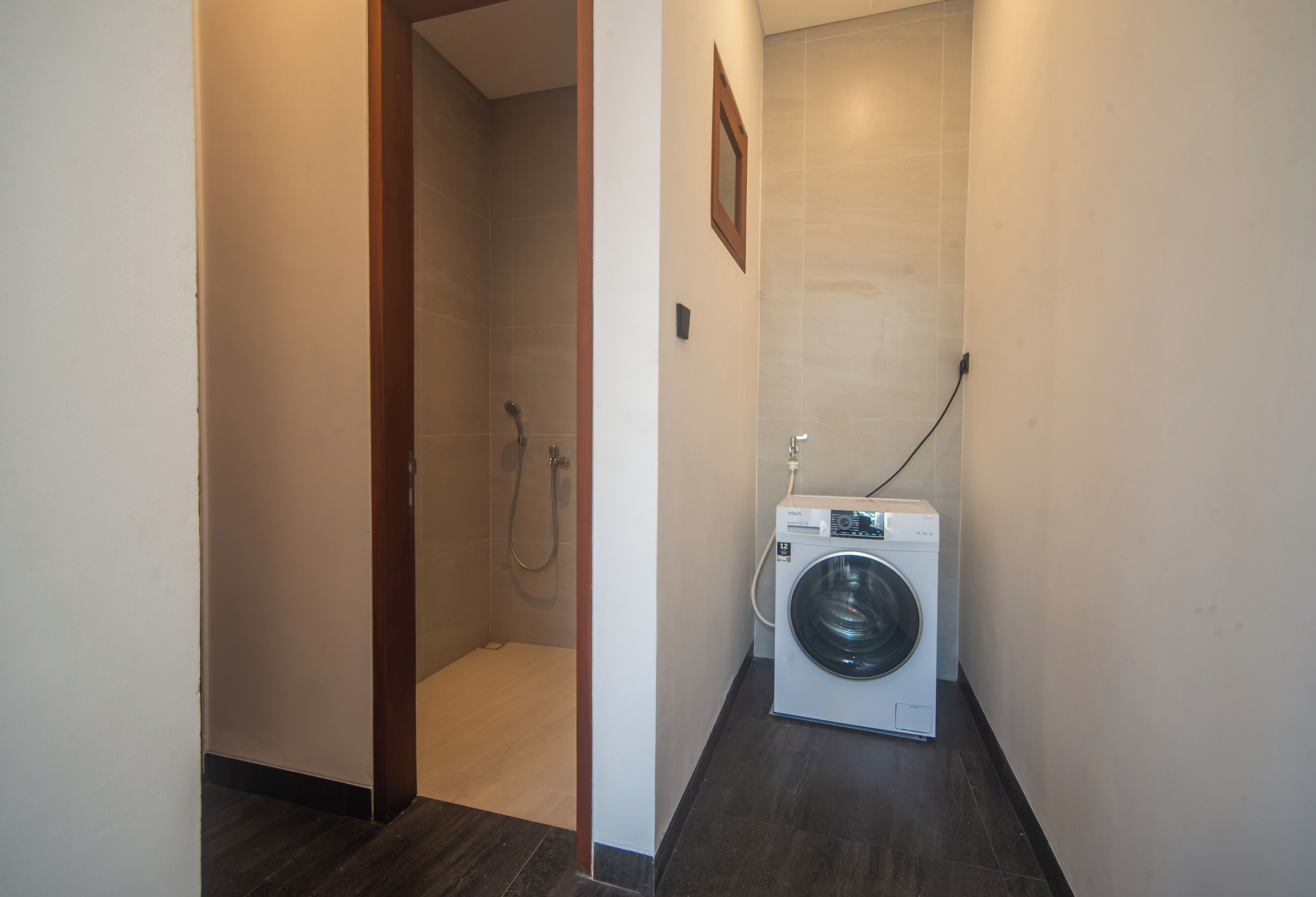 A laundry room with a washing machine and a shower stall.