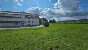 En byggnad med ett rött tegeltak och vita väggar, en gräsklädd åker i förgrunden och en delvis molnig himmel.