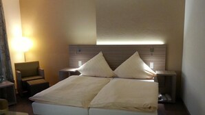 Ett hotellrum med en säng, sängbord, en stol och en lampa.