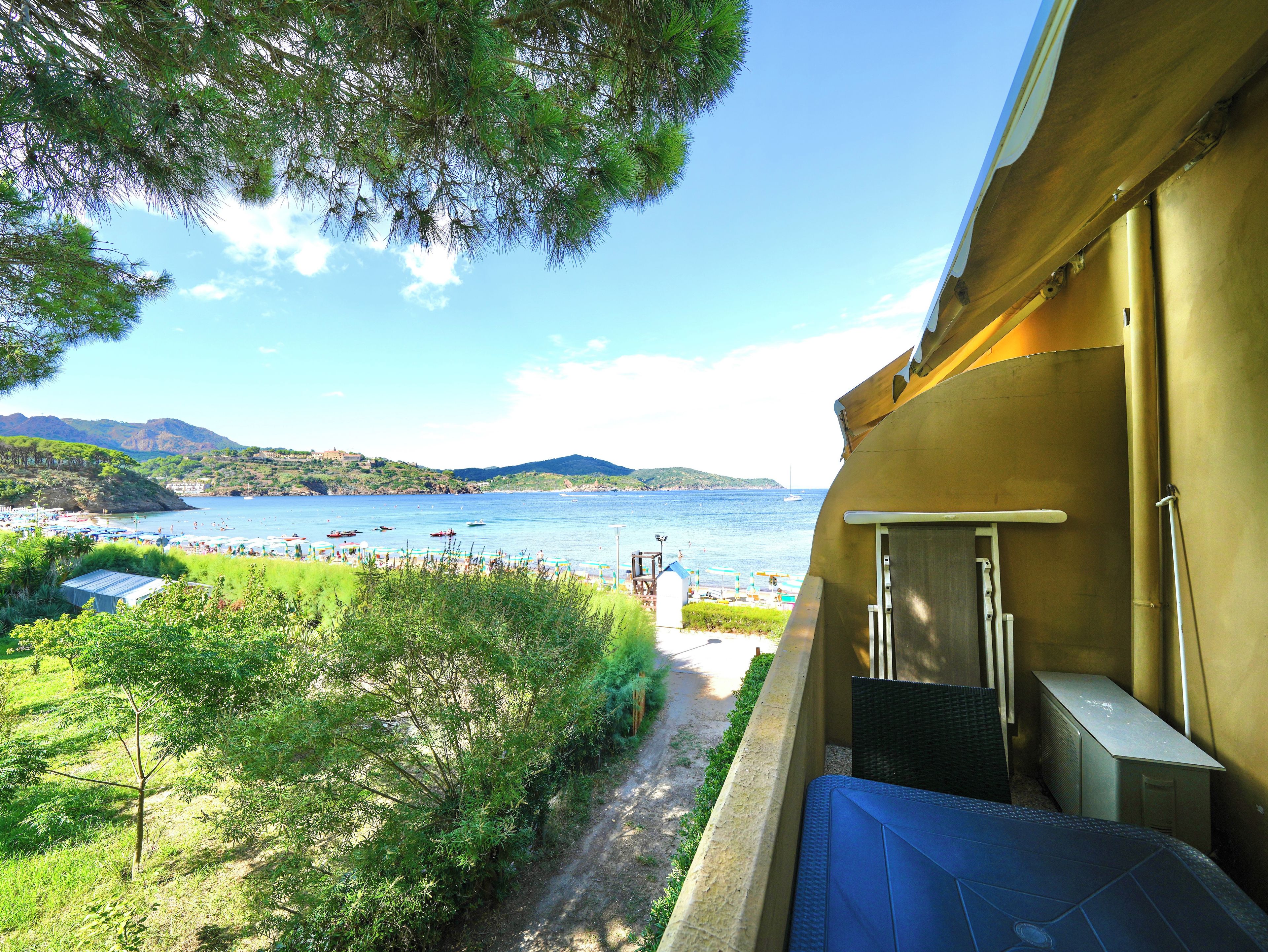 Un balcon offrant une vue sur une zone côtière, notamment une plage et des bateaux sur l’eau.