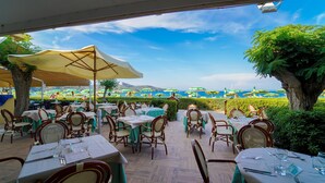 An outdoor dining area with tables and chairs, umbrellas, and a view of the beach. - Residence in Capoliveri just 200 mt from the beach  (Capoliveri)