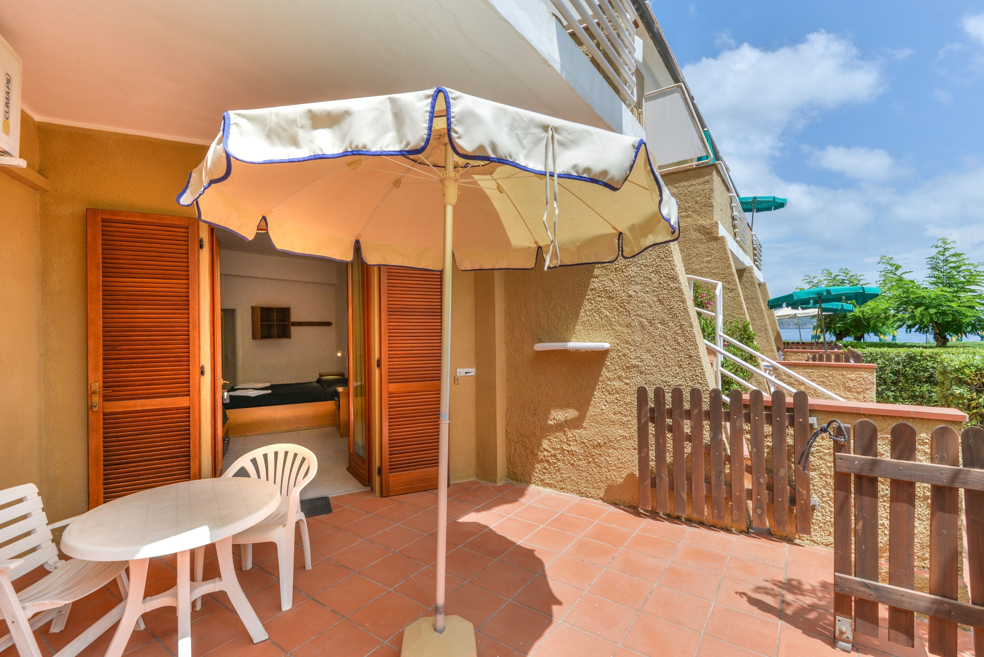 A patio with a table and chairs, an umbrella, and a wooden fence.