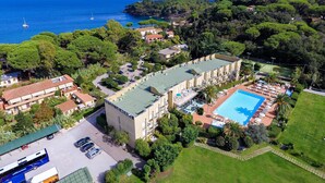 A hotel with a swimming pool, surrounded by lush greenery and a view of the sea. - Residence in Capoliveri just 200 mt from the beach  (Capoliveri)