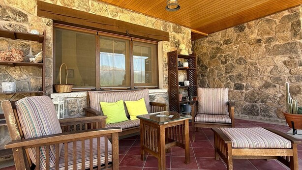 A cozy outdoor seating area with wooden furniture and stone walls. - LOS RELOJES HOUSE (La Adrada)