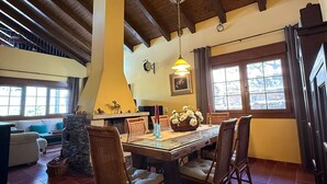 A dining area with a wooden table, chairs, and a hanging light fixture. - LOS RELOJES HOUSE (La Adrada)