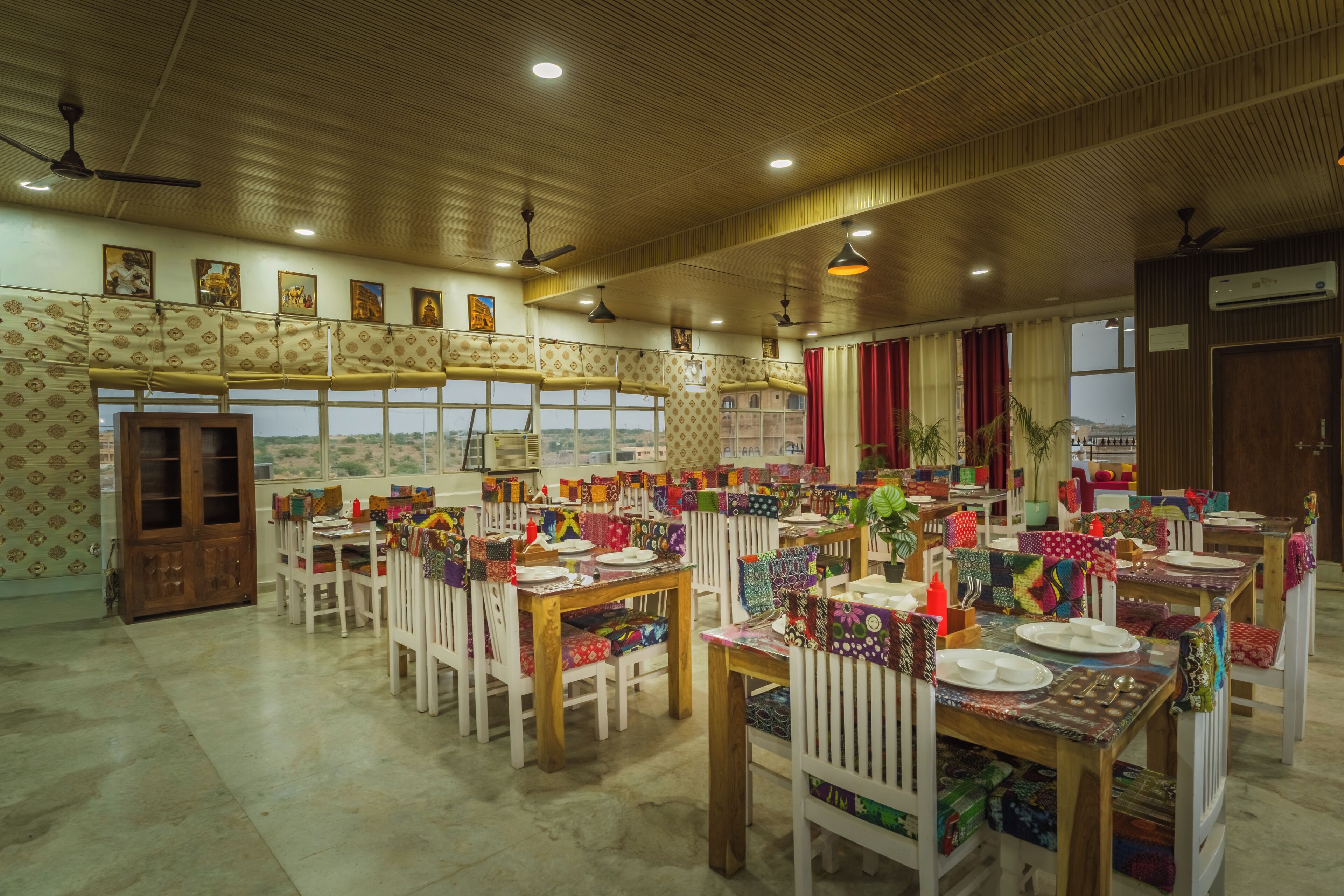 A spacious hall with high ceilings, multiple tables set for dining, and a view of the outdoors through large windows.