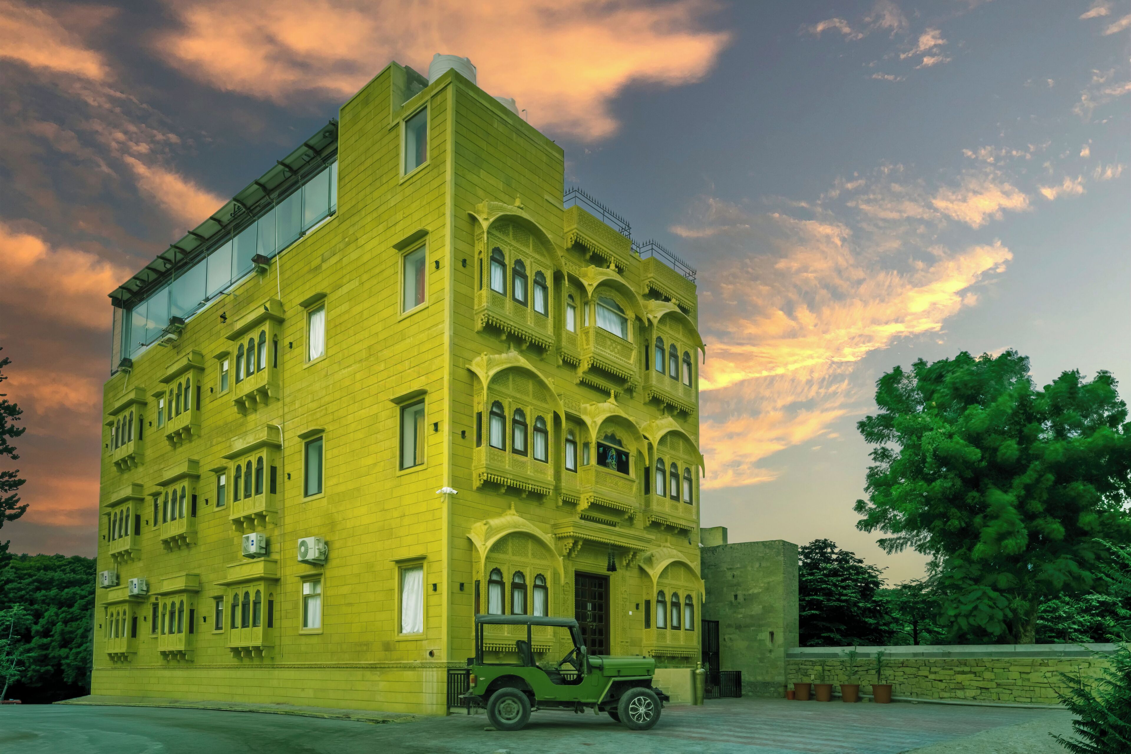 Un edificio de varios pisos con techo plano y ventanas amplias, rodeado de vegetación.