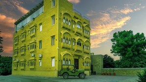 A multi-story building with a flat roof and large windows, surrounded by greenery. - Hotel Narpat Garh Palace Jaisalmer (Jaisalmer)