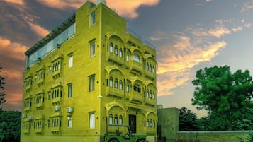Un edificio de varios pisos con techo plano y ventanas amplias, rodeado de vegetación.