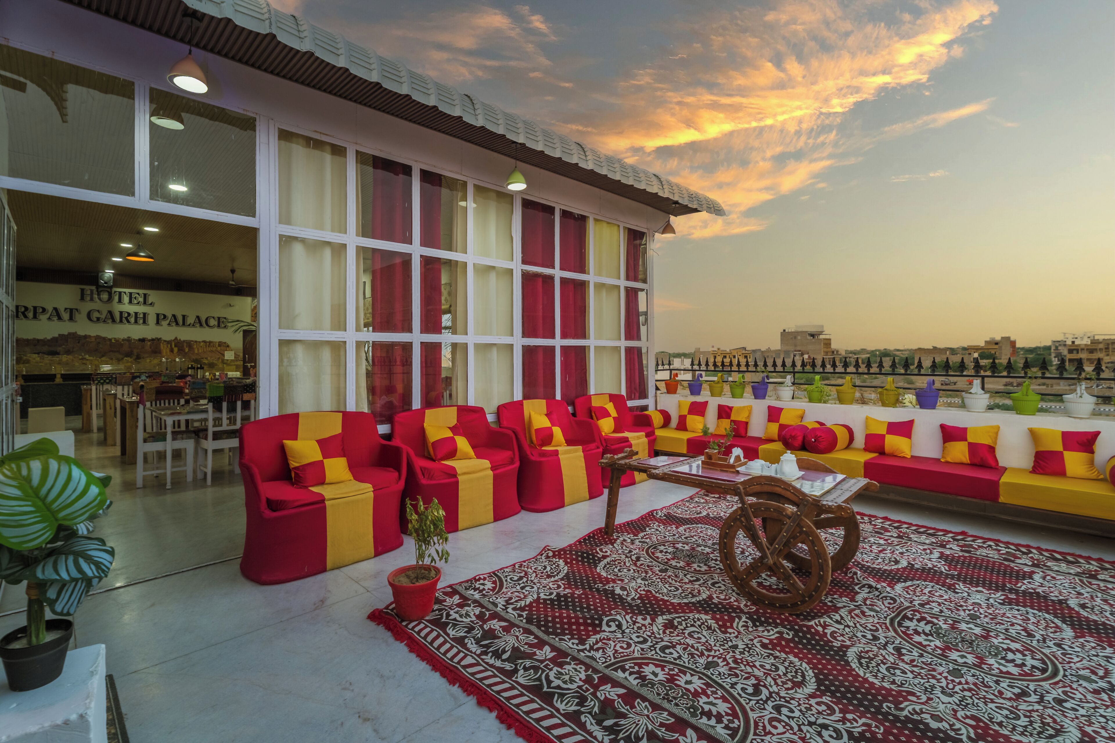 A hotel lobby with a seating area featuring red and yellow sofas, a patterned rug, and a wooden table.