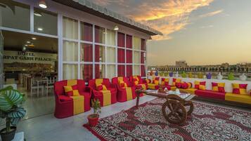 A hotel lobby with a seating area featuring red and yellow sofas, a patterned rug, and a wooden table.