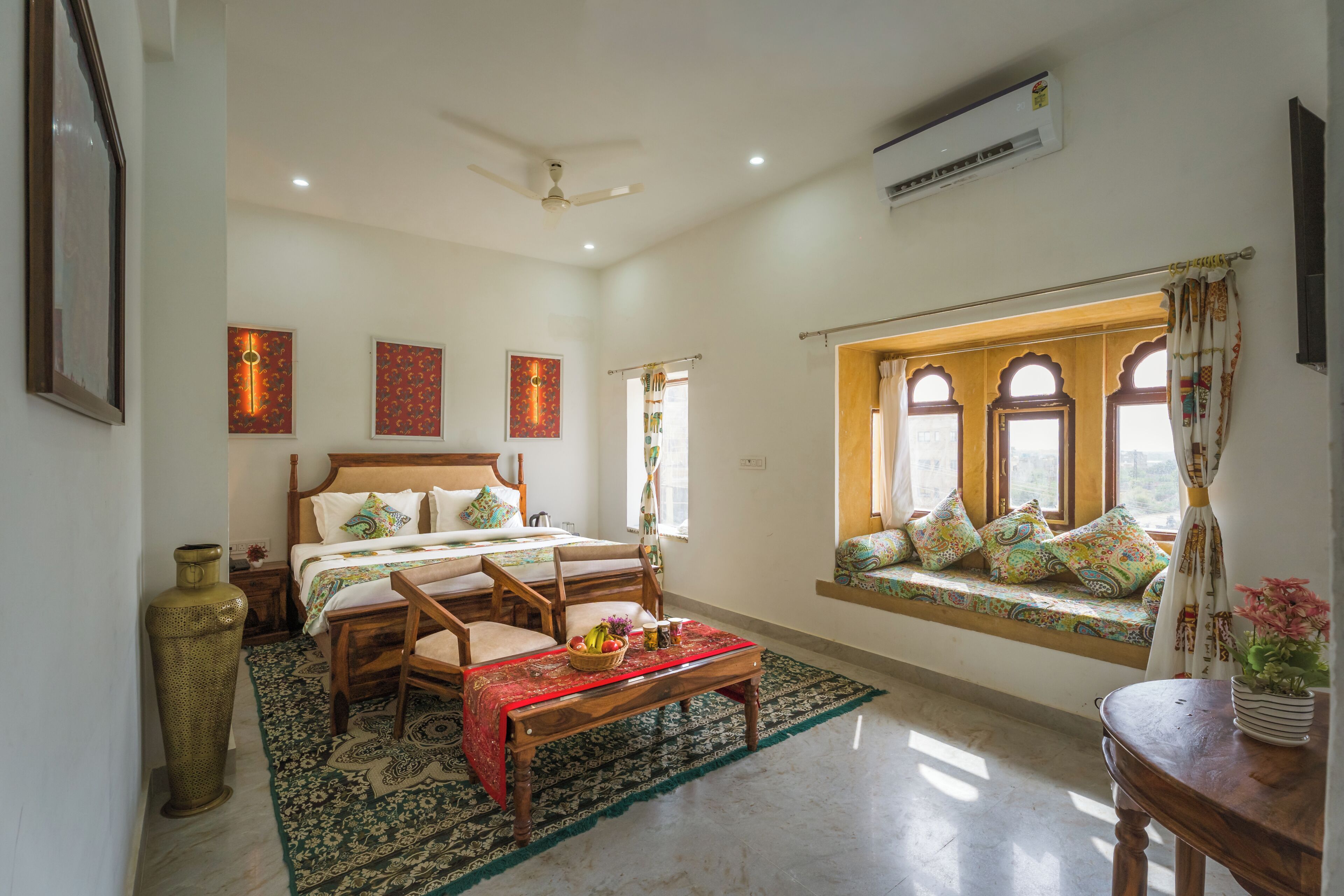 A spacious bedroom with a large bed, a sitting area with a view, and a ceiling fan.