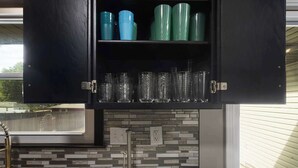 Cozinha com armário preto, painel de azulejos e bancada de granito.
