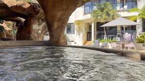 A hot spring area with a large tree and a building with outdoor seating. - 62 at the Caribbean Resort (mooloolaba)
