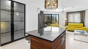 A modern living room with a central island, a yellow sofa, and a glass coffee table. - 62 at the Caribbean Resort (mooloolaba)