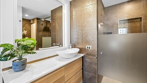 A modern bathroom with a white freestanding sink, a large mirror, and a textured wall. - 62 at the Caribbean Resort (mooloolaba)