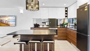 A modern kitchen with a central island, stainless steel appliances, and a pendant light. - 62 at the Caribbean Resort (mooloolaba)
