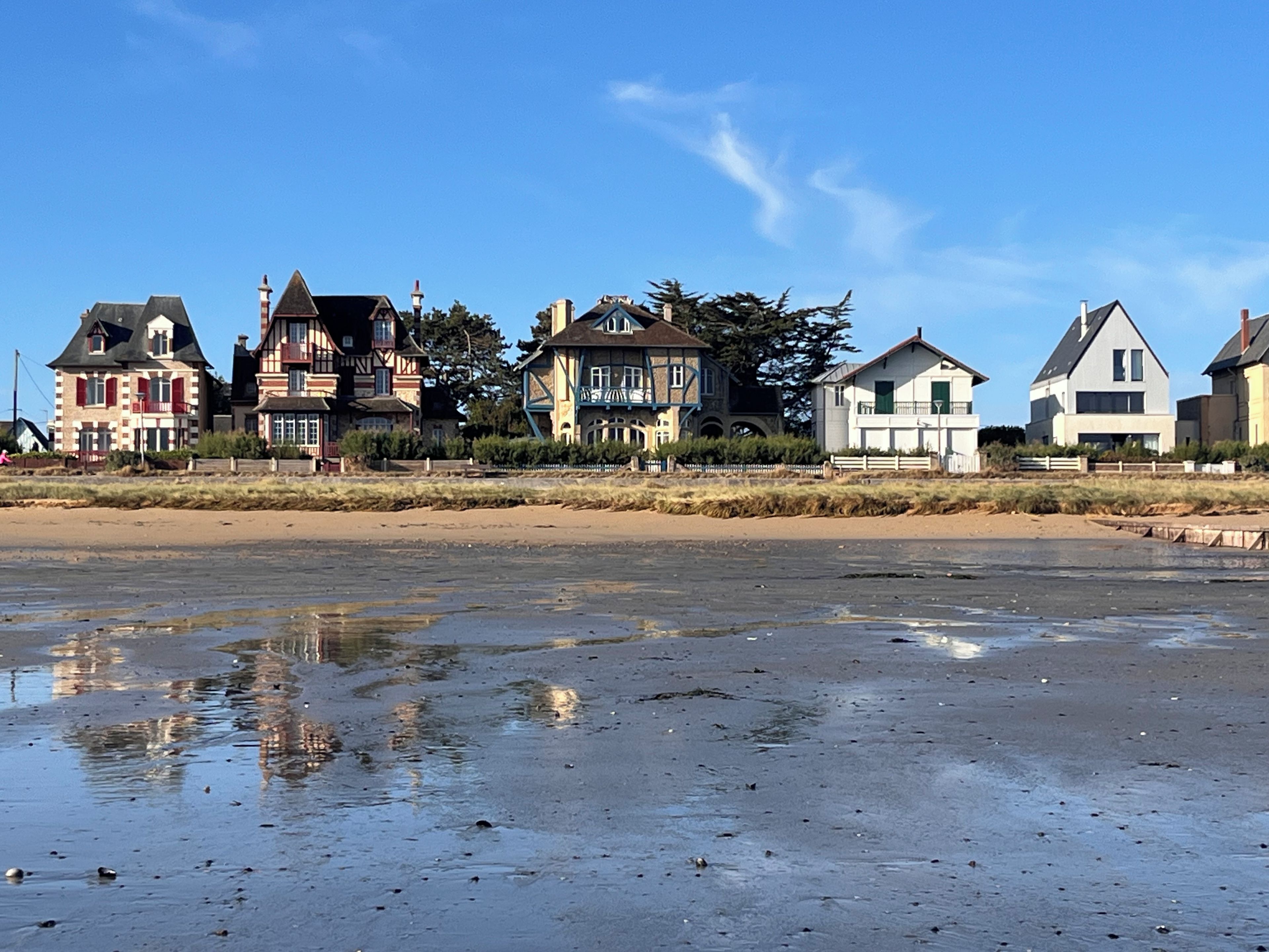 A beachfront property with multiple houses, a sandy beach, and a clear sky.