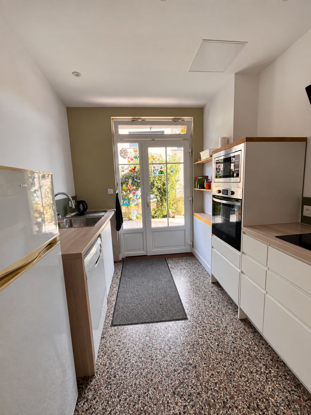 Eine kleine Küche mit Kühlschrank, Backofen und Spüle.