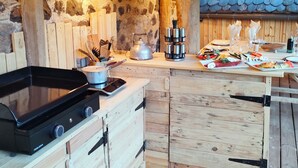 A rustic kitchen with a stove, pots, and a wooden counter with food. - 6-person house in village: hiking, jacuzzi, games room, skiing 10mn away (Thiézac)
