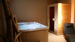 A hot tub with a wooden bench, a sauna, and a massage chair in a room with beige walls. - 6-person house in village: hiking, jacuzzi, games room, skiing 10mn away (Thiézac)