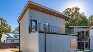 A modern two-story building with a flat roof, large windows, and a balcony. - Tiny Home Atlanta Retreat (Union City)