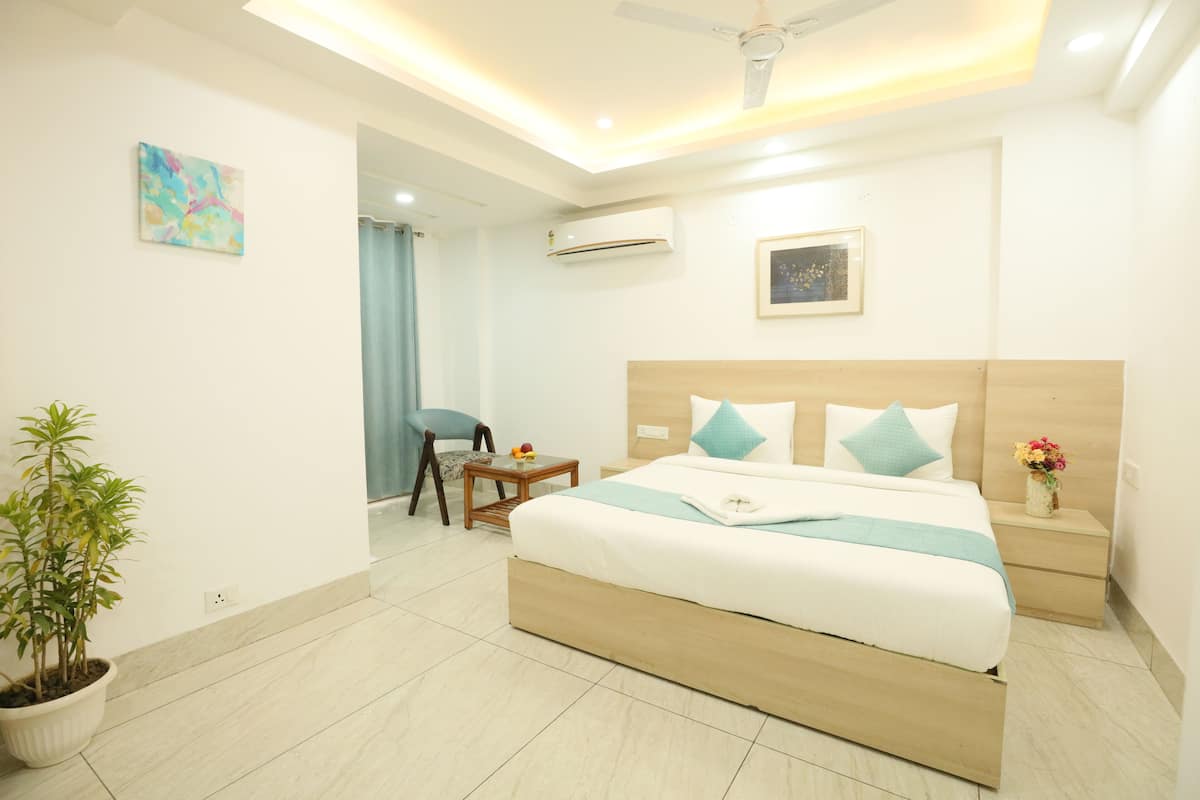 A modern hotel room with a large bed, bedside tables, a small table with fruits, a potted plant, and a ceiling fan.