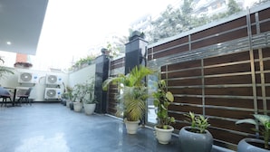 Un espacio exterior moderno con plantas en macetas, unidades de aire acondicionado y una valla de madera.