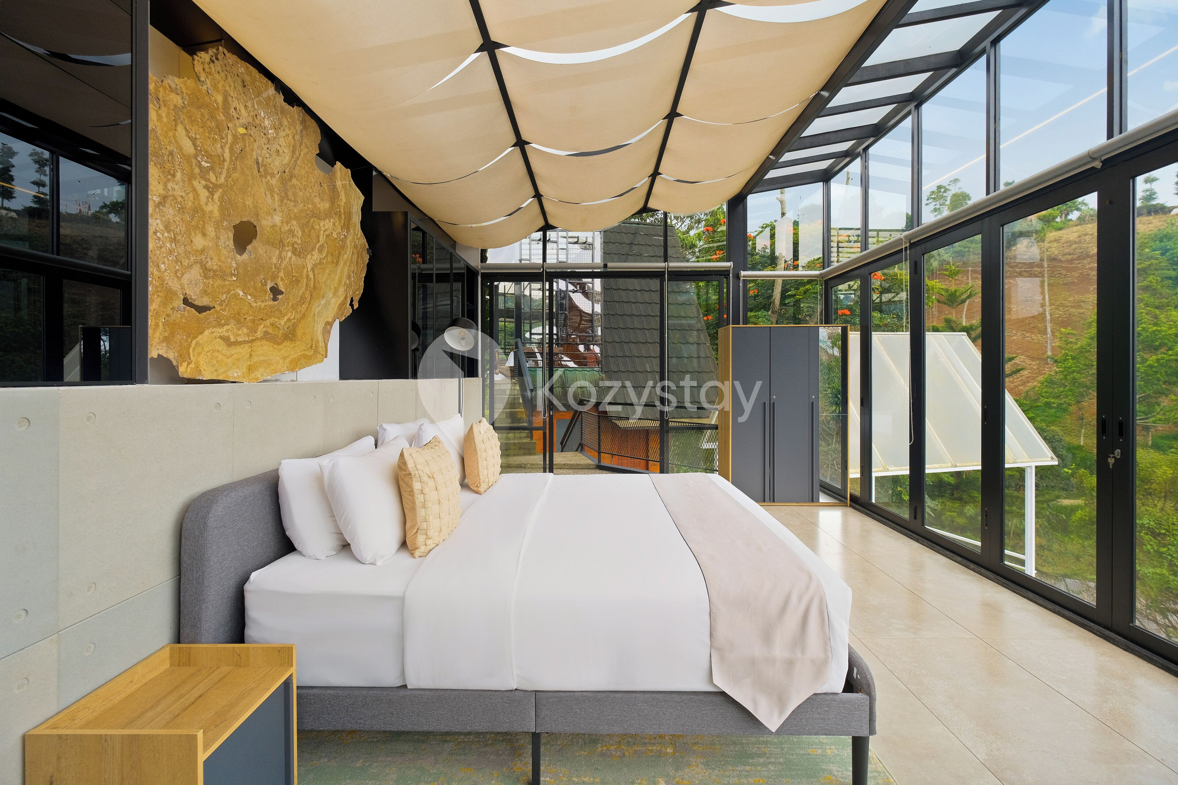 Quarto moderno com cama grande, mesa de cabeceira de madeira e uma janela ampla com vista para o exterior.