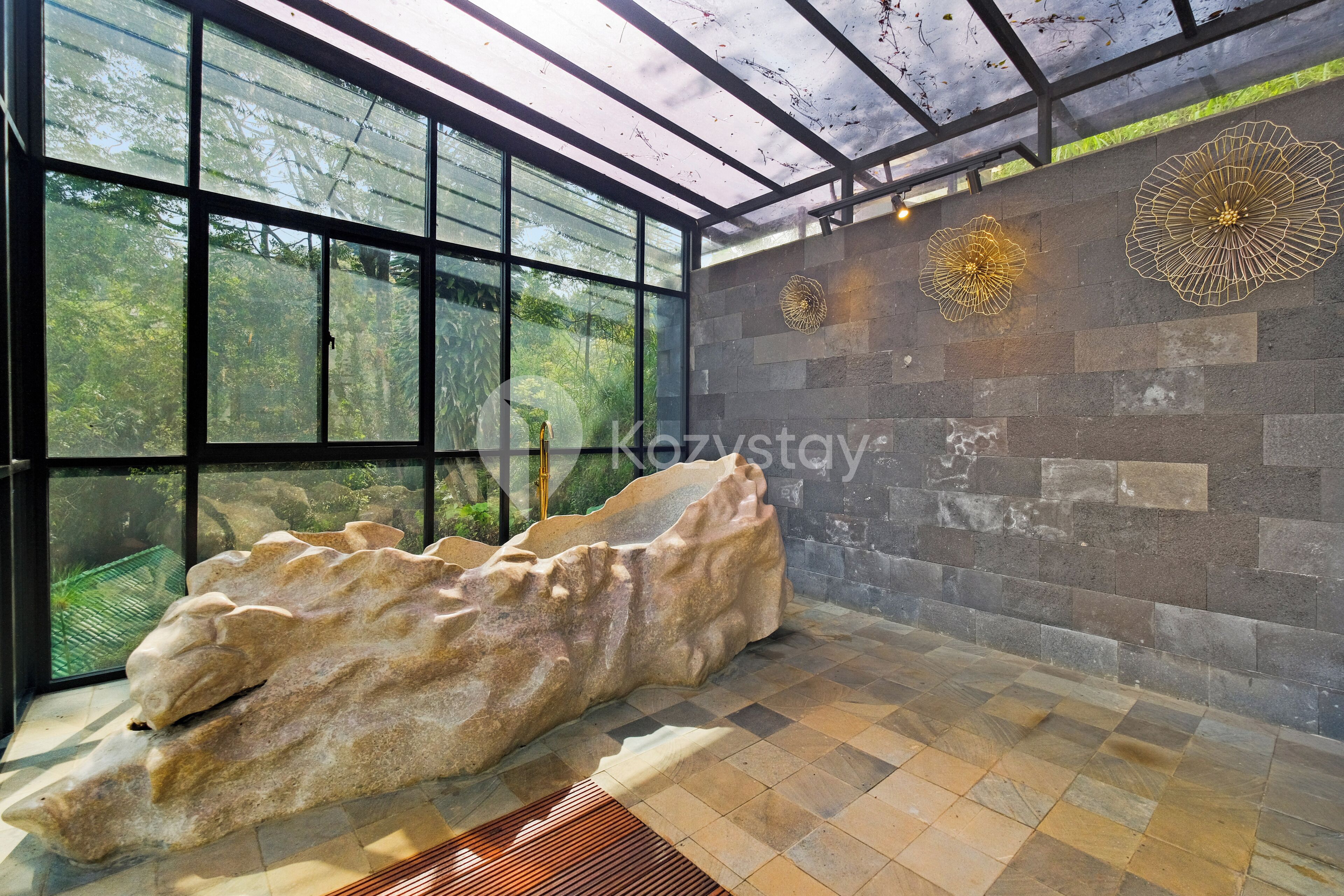 A modern interior with large windows, a stone wall, and a unique rock sculpture.