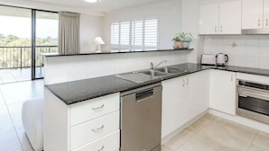 Una cucina moderna con mobili bianchi, un piano di lavoro nero, lavastoviglie, lavello e fornello.