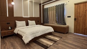 A modern bedroom with a large bed, a bedside table, a wooden bench, and a wooden door.