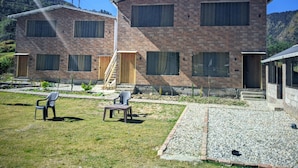 A two-story building with a brick exterior, multiple windows, and a small outdoor seating area with chairs and a table.