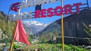 A sign for Nawalam Swiss Resort with a mountainous backdrop.