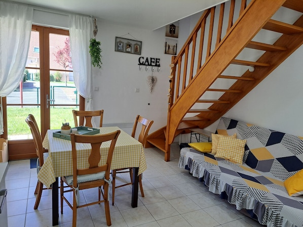 Un comedor con una mesa y sillas, una escalera y un sofá con cojines estampados.