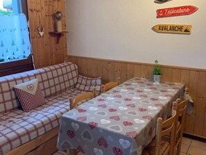 A cozy room with a checkered sofa, a dining table with a heart-patterned tablecloth, and wooden walls. - Charming apartment with Wifi in Samoëns (Samoëns)