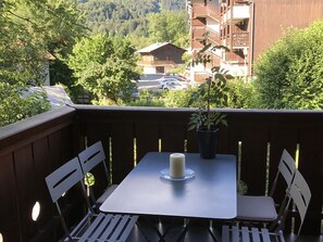 A balcony with a table and chairs, a potted plant, and a candle.