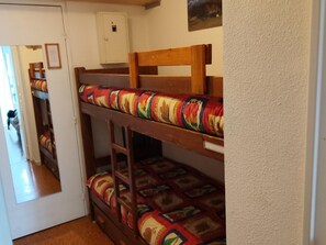 Ein Stockbett mit einer Leiter, eine weiße Tür und ein kleines Schränkchen.