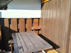 A wooden table with a metal frame, set against a wooden fence and a white wall. - Cozy studio for 4 people in Samoëns (Samoëns)