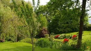 A lush garden with a variety of trees, flowering plants, and a well-maintained lawn. - Detached house with terrace, pellet stove and peaceful garden. (Canisy)