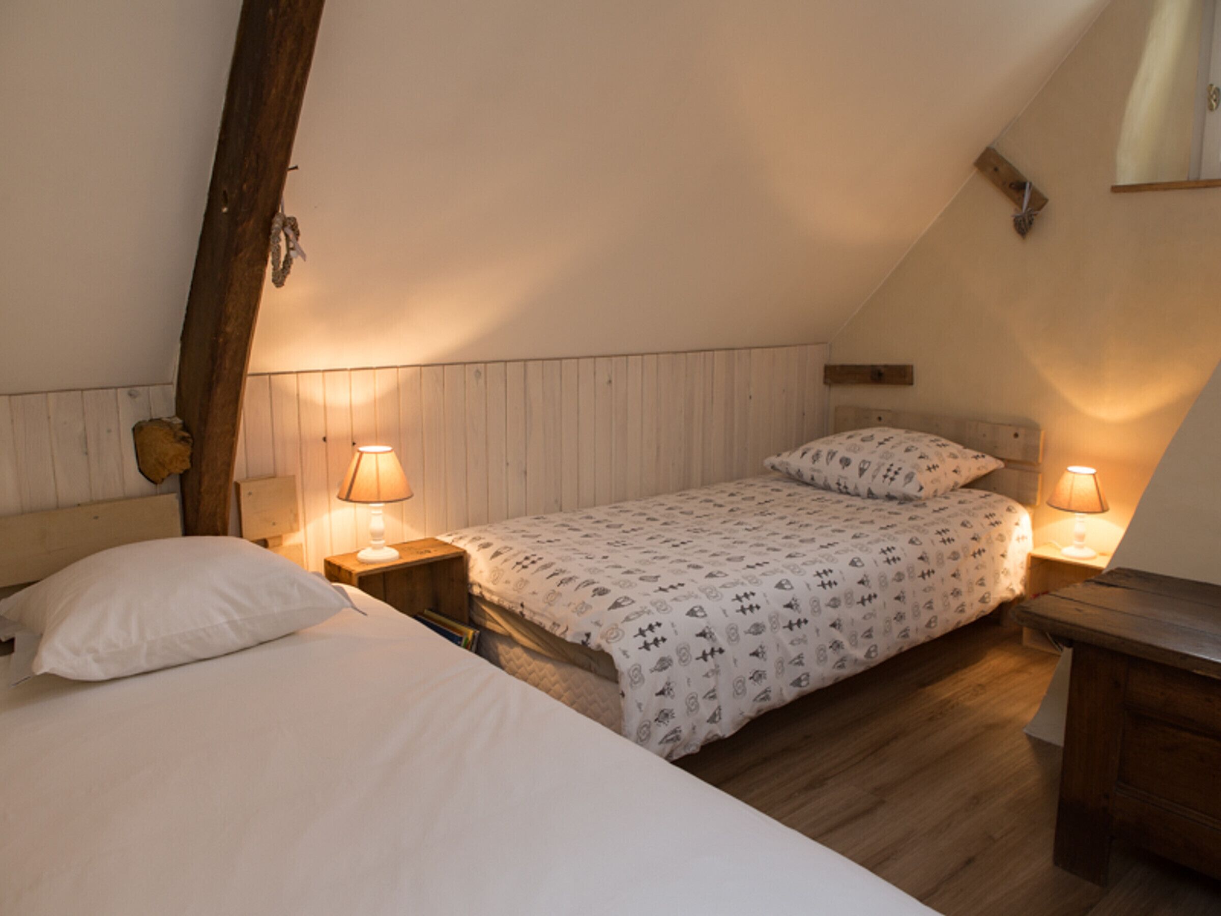 A bedroom with two beds, wooden headboards, and bedside lamps.