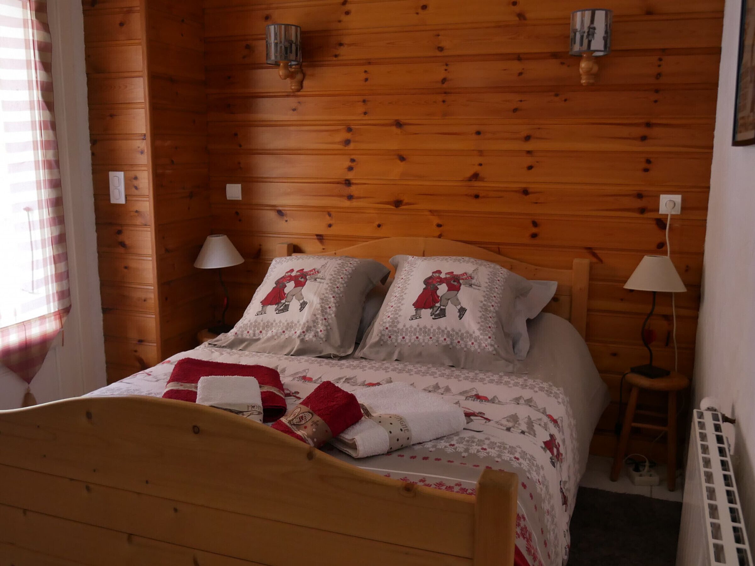 A wooden-paneled bedroom with a bed, two bedside lamps, and a radiator.