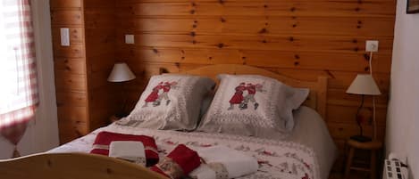 Un dormitorio con paneles de madera, una cama, dos lámparas de noche y un radiador.