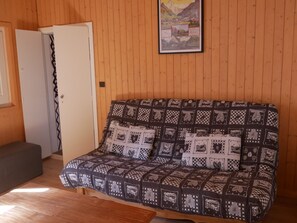 A cozy room with a patterned sofa, a wooden floor, and a door.