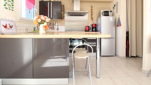 Een moderne keuken met roestvrijstalen apparatuur, een houten aanrecht en een klein eethoekje met een stoel.