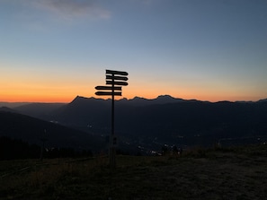 A signpost with multiple directional arrows against a sunset backdrop.