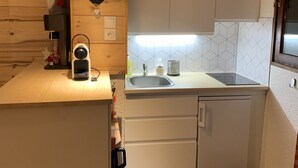 Eine kleine Küche mit Holzwänden, einer weißen Arbeitsplatte, einem Spülbecken und einer leuchtenden Lampenform im Herzen.