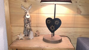 Ein Nachttisch aus Holz mit einer Lampe, einem dekorativen Rentier und sternförmigen Ornamenten.