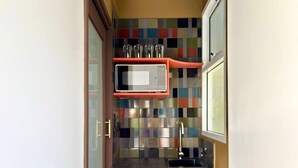 A compact kitchen with a microwave, a sink, and a colorful tile backsplash.